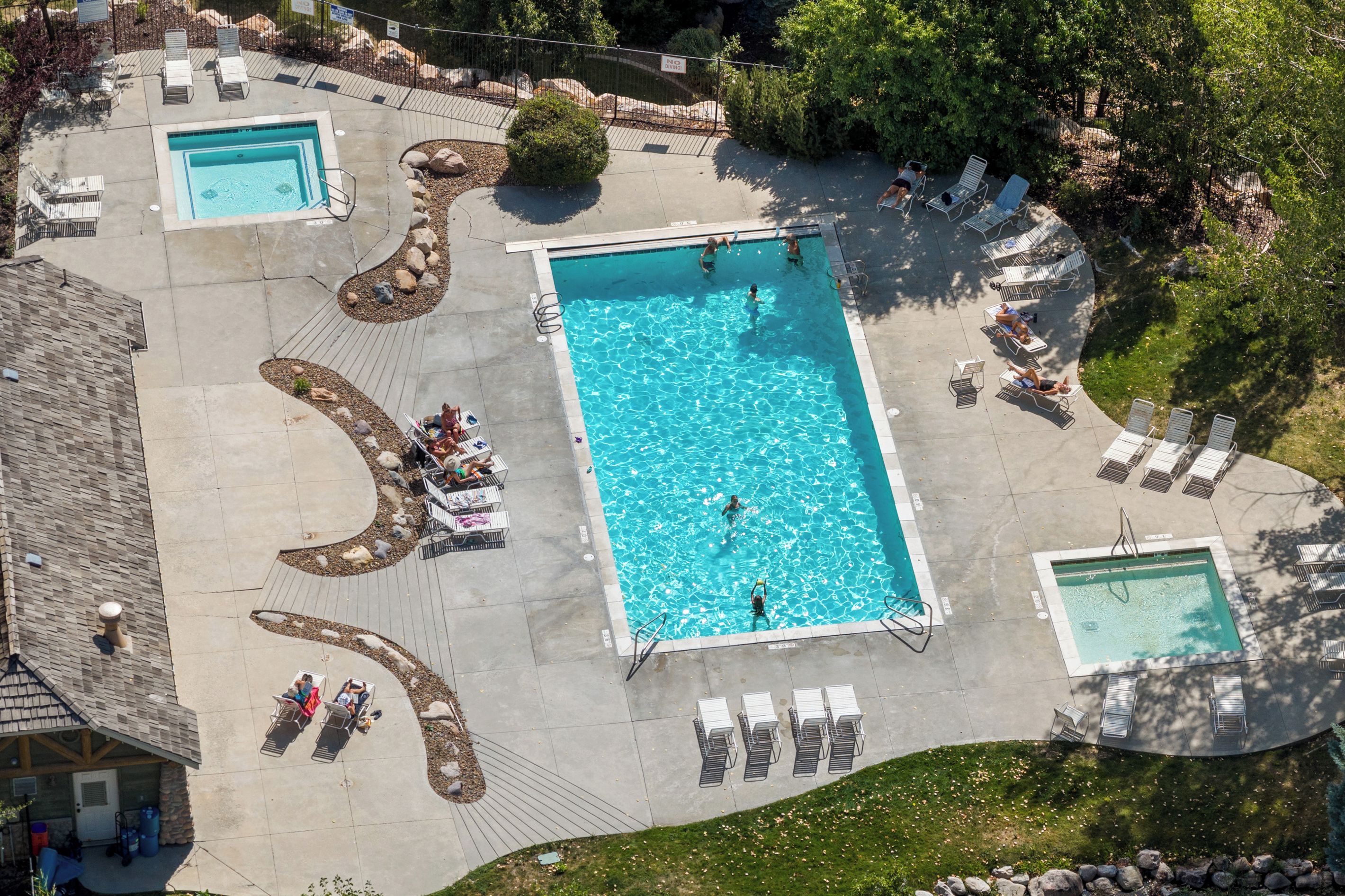 Una gran piscina rectangular rodeada de tumbonas y un área de estar cubierta.