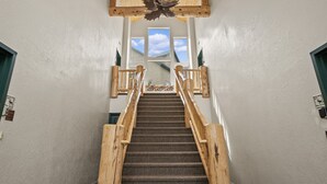 Eine Holztreppe mit Blick auf den Himmel durch große Fenster im oberen Bereich.