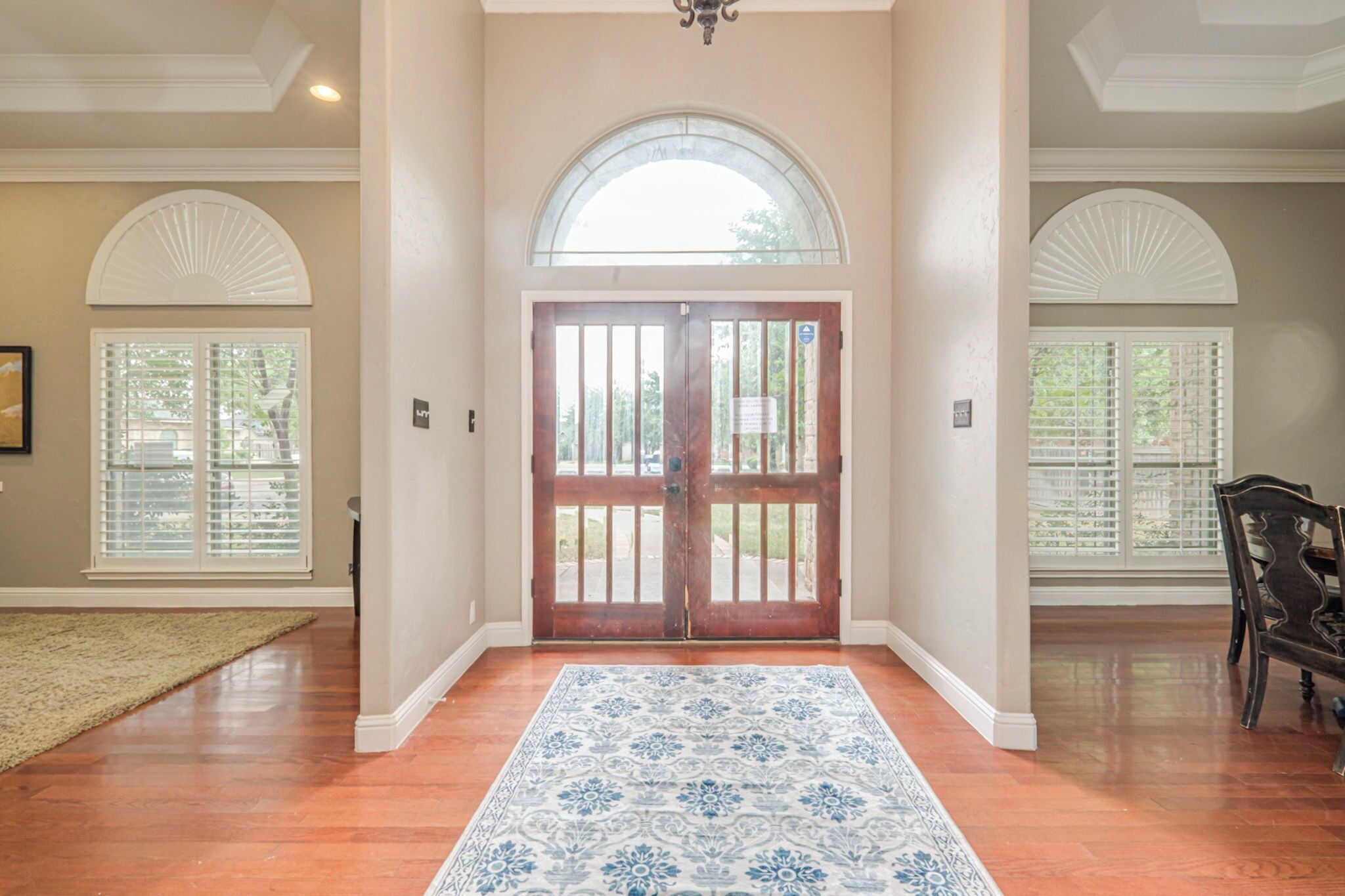 A hallway with a wooden door, a patterned rug, and a chair.