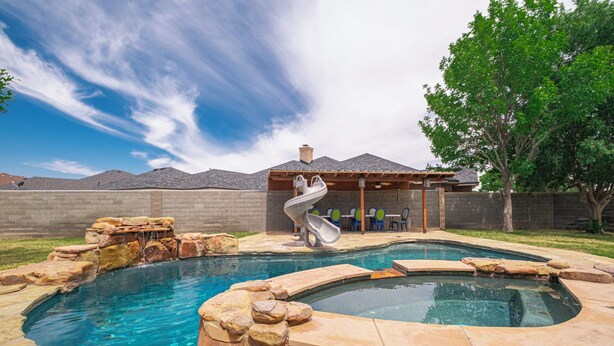 Un jardin avec une piscine, un jacuzzi et un toboggan.