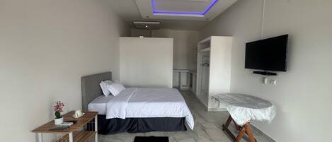 Quarto de hotel moderno com cama, televisão, escrivaninha e closet espaçoso.