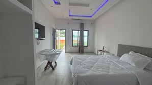 A modern bedroom with a large bed, a desk, and a TV. - Mangungumete Motel (Magungumete)