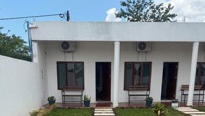 A pathway leading to a modern building with a white exterior, large windows, and a covered entrance. - Mangungumete Motel (Magungumete)