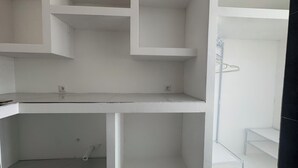 A room with a white desk, a white shelving unit, and a white shower area. - Mangungumete Motel (Magungumete)