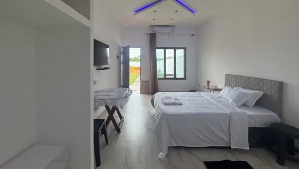 A modern bedroom with a bed, bedside table, and a TV mounted on the wall. - Mangungumete Motel (Magungumete)