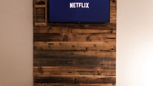 Una habitación con pared de madera y un televisor montado que muestra el logotipo de Netflix.