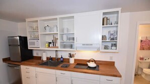 Una cocina moderna con armarios blancos, un refrigerador de acero inoxidable y una encimera de madera.