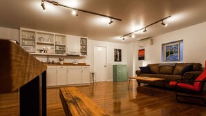 Una cocina moderna con armarios blancos, una mesa de comedor de madera y un sofá de cuero marrón.