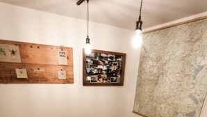 Una mesa de madera para comer con bancos, una lámpara colgante, un tablón de anuncios y un mapa en la pared.