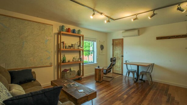 Una sala de estar acogedora con una mesa de centro de madera, un sofá, una estantería y un comedor con una mesa y sillas.