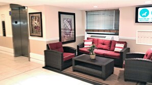 A lobby with a sofa set, chairs, a coffee table, and framed artwork on the walls.