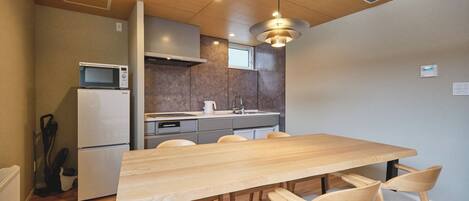 A modern kitchen with a wooden table and chairs, a microwave, and a refrigerator.