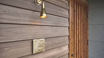 A wall with horizontal wooden panels and a brass wall-mounted light fixture.