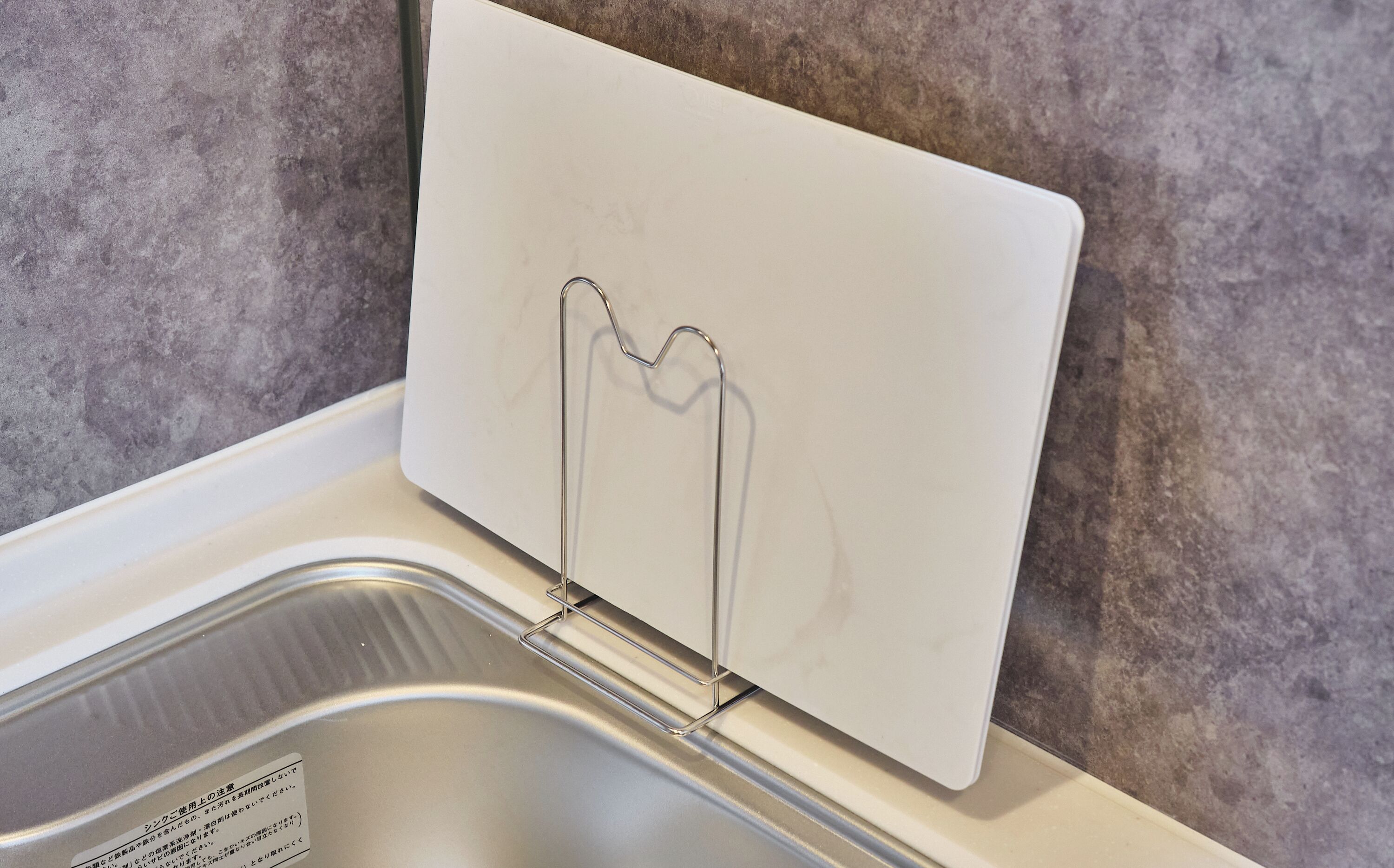 A kitchen sink with a white countertop and a stainless steel basin.
