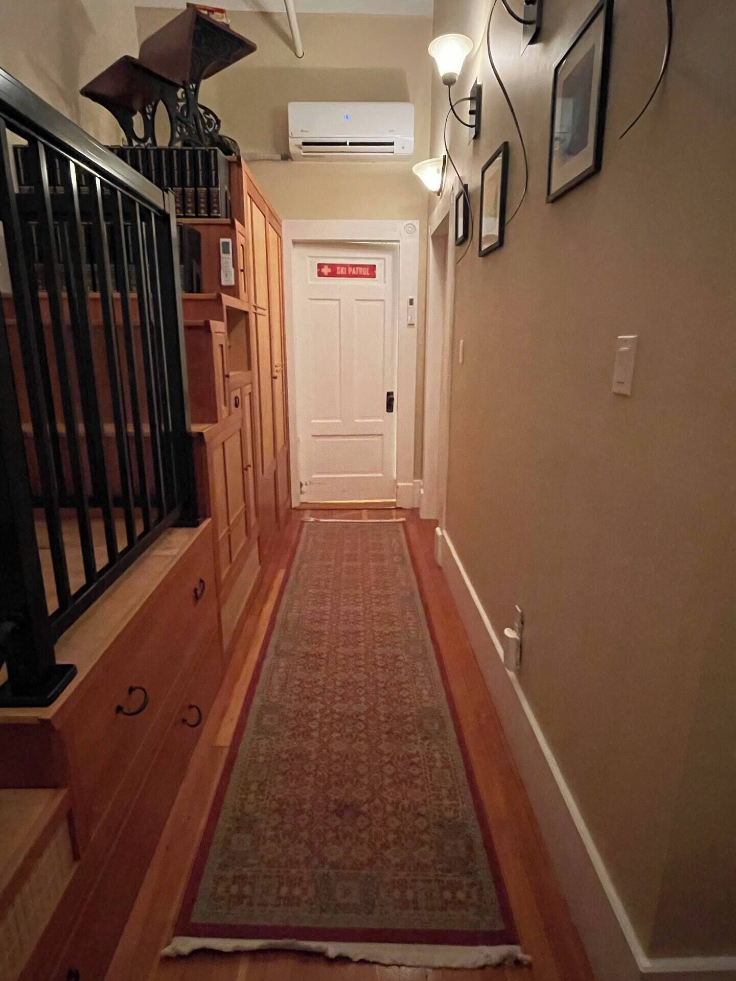 Un pasillo con una escalera de madera, una alfombra roja y una puerta con la leyenda 'Ski Patrol'.