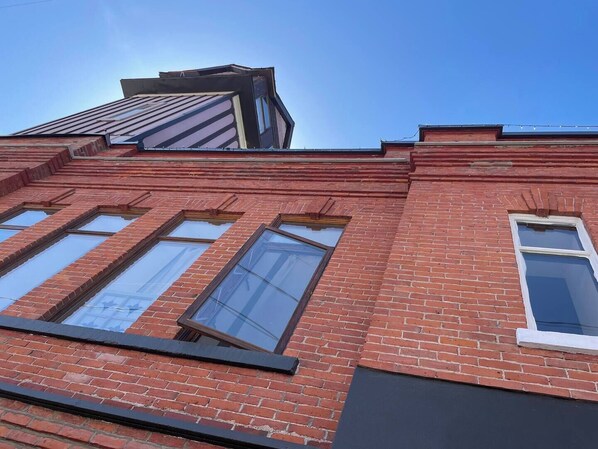 A red brick building with large windows and a sloped roof. - Old Firehall - Haddie Brown (Rossland)