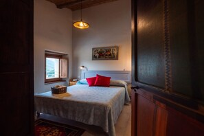 Une chambre à coucher avec un lit, une fenêtre, un tableau et un luminaire suspendu.
