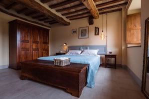 Une chambre à coucher avec un lit en bois, une table de chevet, une commode en bois et un grand miroir.