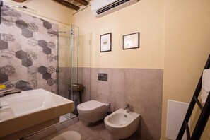Une salle de bain avec une douche à parois de verre, un bidet, des toilettes et un lavabo.