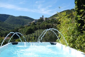 Een whirlpool met waterstralen, omgeven door weelderige begroeiing en een bergachtig landschap.