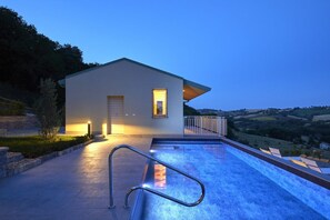 A modern house with a swimming pool, a covered patio, and a view of the countryside. - Villa le Moie by MMega (Arcevia)