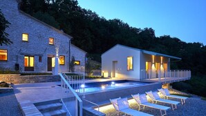 Ein modernes Haus mit Schwimmbad, Sitzgelegenheit im Freien und einem Steinhaus.