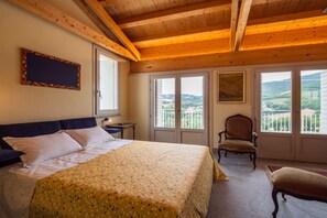 Une chambre à coucher avec un lit, une chaise, un bureau et une fenêtre donnant sur un beau paysage.