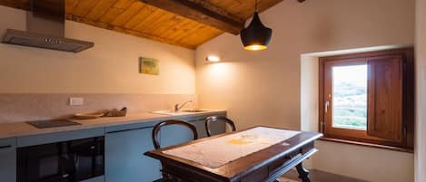 Una cocina con techo de madera, una mesa de comedor con sillas, un ventanal con vistas y un horno empotrado.
