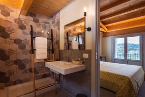 Een badkamer met een witte wastafel, een spiegel en een douche.