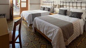 Een hotelkamer met twee bedden, een houten stoel, een tafel en een vloer met een patroon.