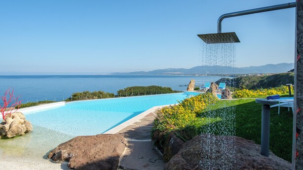 Ein klarer, blauer Himmel, ein Schwimmbecken und Blick auf das Meer.