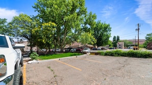 A parking lot with a white SUV parked on the left. - Atomic #3 I Downtown I Historic I Trailer Parking (Moab)