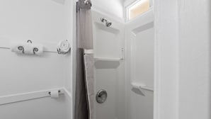 A bathroom with a shower, a toilet, and a towel rack with towels. - Atomic #3 I Downtown I Historic I Trailer Parking (Moab)