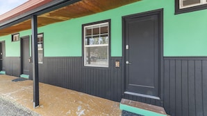 A building with a green exterior and black trim, featuring a single door and windows. - Atomic #3 I Downtown I Historic I Trailer Parking (Moab)