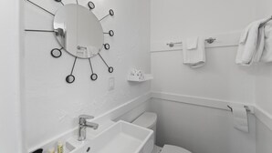 Een moderne badkamer met een spiegel in het midden, een wastafel en een toilet.