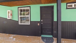 Un edificio con una puerta negra, una ventana y una pared verde.