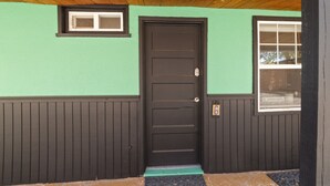 A house with a dark wooden door, a small window above the door, and a larger window to the right. - Atomic #6 I Downtown I Historic I Trailer Parking (Moab)