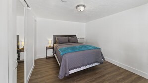 A bedroom with a bed, nightstand, and a ceiling light. - Atomic #6 I Downtown I Historic I Trailer Parking (Moab)