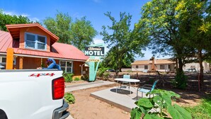 A white pickup truck parked in front of a motel with a red roof and a sign that reads "Atomic Motel Office". - Atomic #6 I Downtown I Historic I Trailer Parking (Moab)