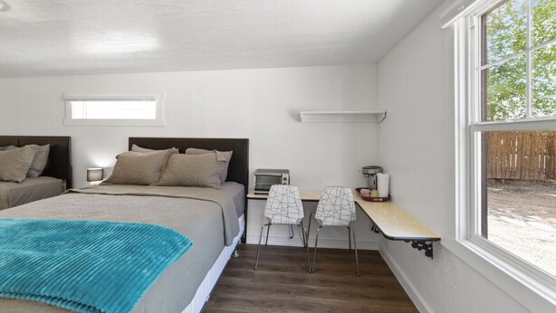 A bedroom with two beds, a desk, and a chair.