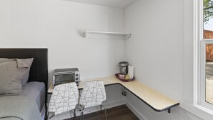 A compact room with a bed, a kitchenette, a small table, and a window.