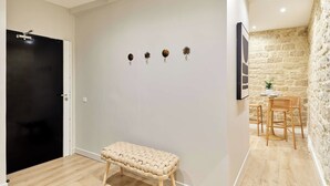 A room with a black door, a bench, a wall-mounted light fixture, and a stone wall. - Charming Apartment Center of Paris by Studio Prestige (Paris)