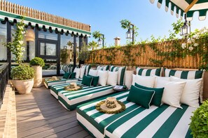A deck with striped outdoor seating, potted plants, and a wooden fence.