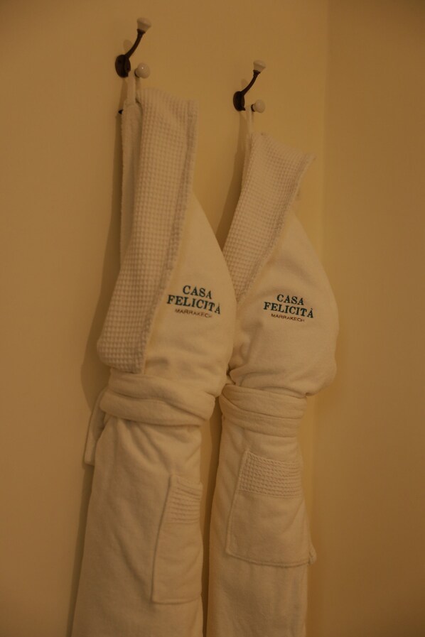 Two white robes hanging on hooks with the text "CASA FELICITÀ" on them. - Riad Casa Felicità (Marrakech)