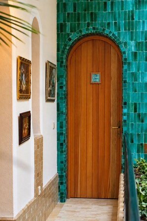 Une porte en bois avec une enseigne au-dessus, un mur recouvert de carreaux et des tableaux encadrés accrochés au mur.