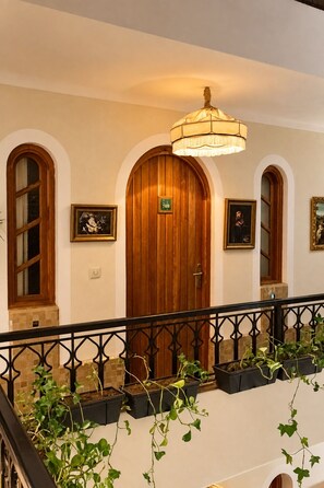 A hotel lobby with wooden doors, a chandelier, framed artwork, and potted plants. - Riad Casa Felicità (Marrakech)