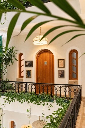 A hotel lobby with a wooden door, framed artwork, and a hanging light fixture. - Riad Casa Felicità (Marrakech)