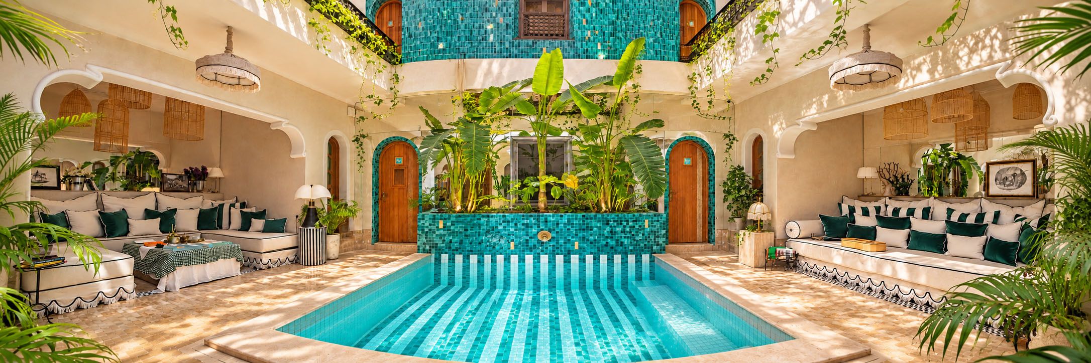 Un área de piscina interior lujosa con suelo de baldosas, rodeada de asientos y abundante vegetación.