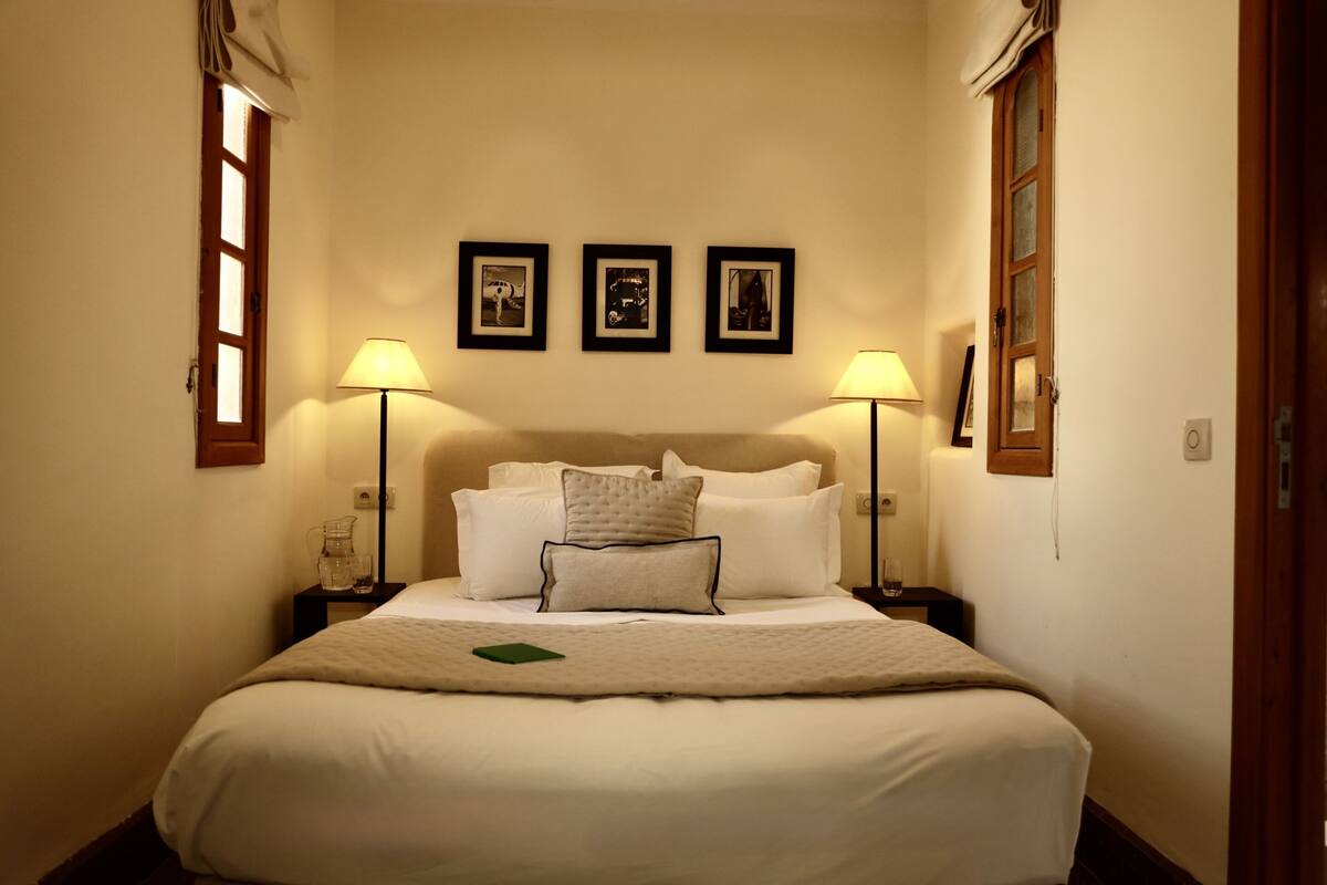 A neatly arranged hotel room with a large bed, two bedside tables, and three framed pictures on the wall.