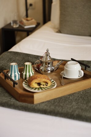 A tray with a teapot, a cup, two sugar bowls, and a pastry on a bed. - Riad Casa Felicità (Marrakech)